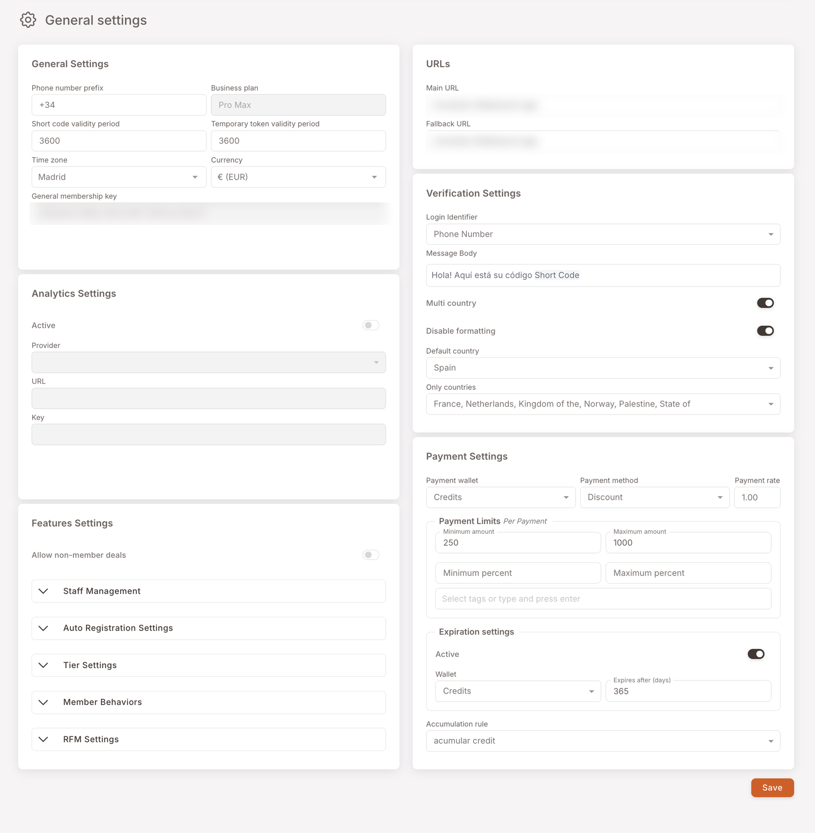 The General settings page, laid out as two columns of cards. Left column: General Settings (phone number prefix +34, business plan, short-code and temporary-token validity periods, time zone Madrid, currency € EUR, general membership key); Analytics Settings (Active toggle, Provider, URL, Key); Features Settings (Allow non-member deals toggle plus collapsible accordions — Staff Management, Auto Registration Settings, Tier Settings, Member Behaviors, RFM Settings). Right column: URLs (Main URL, Fallback URL); Verification Settings (Login Identifier, Message Body, Multi country, Disable formatting, Default country, Only countries); Payment Settings (Payment wallet Credits, Payment method Discount, Payment rate, Payment Limits, Expiration settings, Accumulation rule). A Save button sits at the bottom-right.